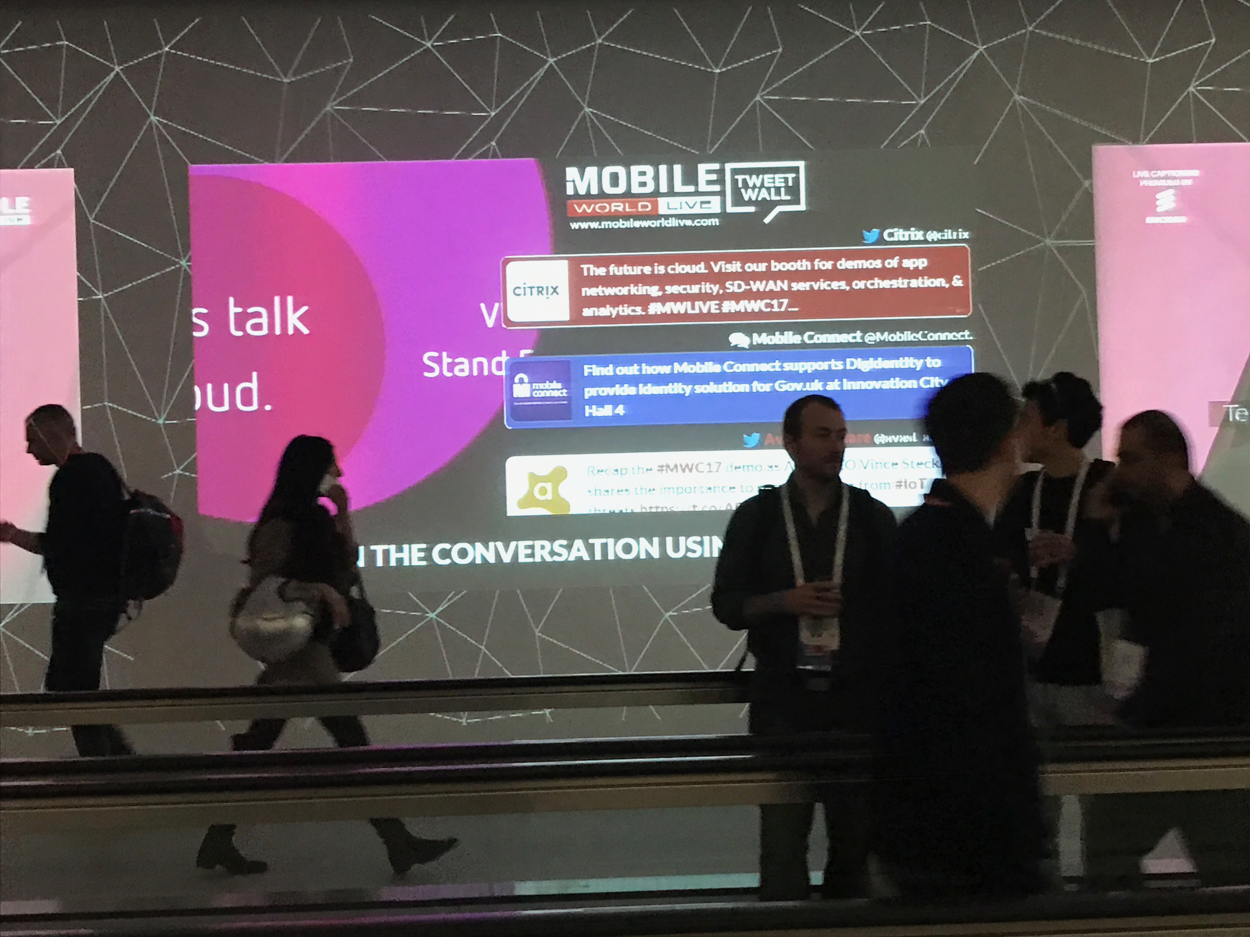 social wall projected on a wall next to moving walkway
